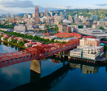 Aerial view of downtown Portland with bridges crossing the Willamette River at sunrise.