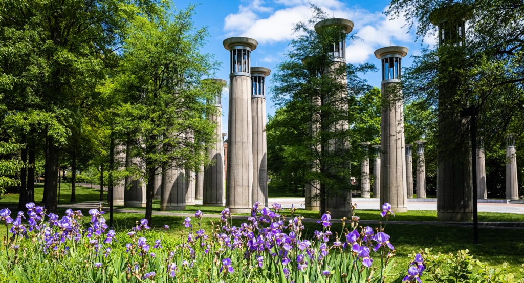 Concrete bell towers of the Nashville Bicentennial Mall Carillon framed by spring flowers and greenery