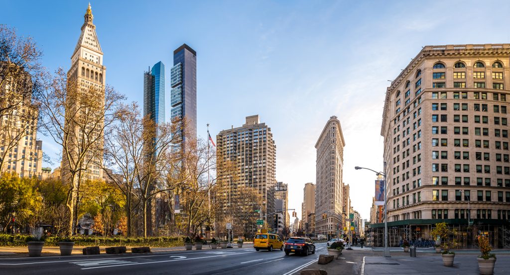 Flatiron Plaza with people and cafés facing the Flatiron Building