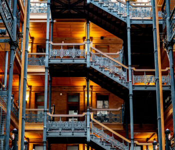 Interior of the Bradbury Building with ornate ironwork, warm lighting, and open stairways.