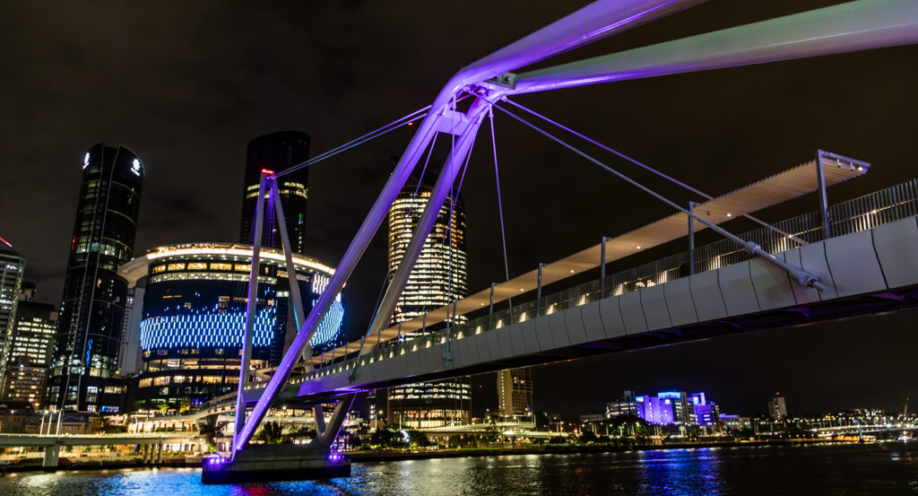 Modern white suspension bridge glowing with city lights in Brisbane