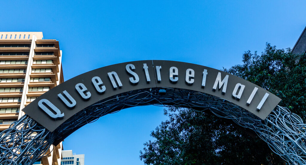 Queen Street Mall sign with buildings and trees in Brisbane city