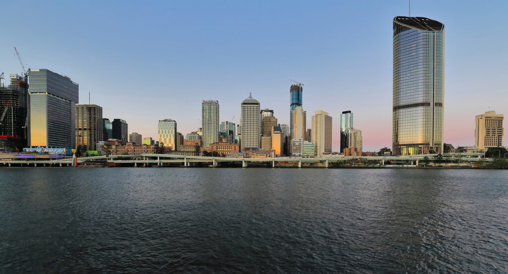 Glass façade of Brisbane Skytower reflecting the sunset across the river
