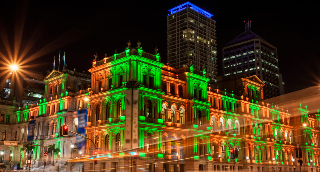 Exterior of Brisbane’s Treasury Hotel glowing in green and orange lighting