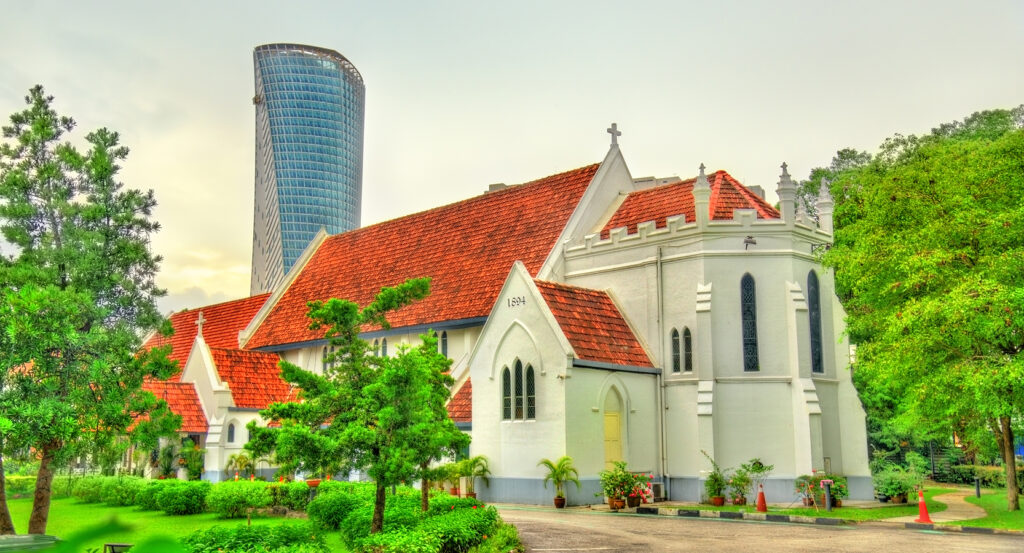 Colonial-era St. Mary’s Cathedral framed by gardens and modern skyscrapers in Malaysia.