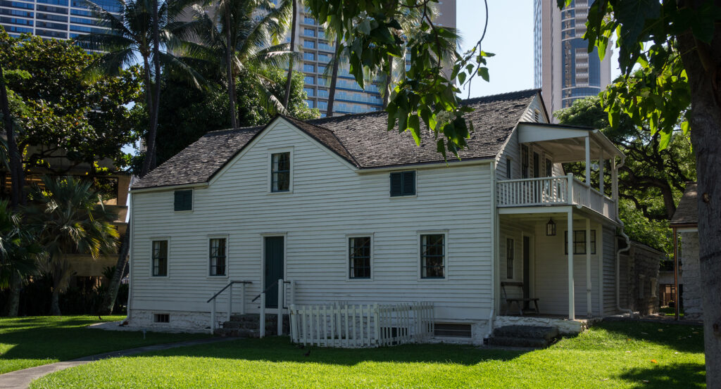 Historic Mission Houses in Honolulu framed by palm trees and skyline