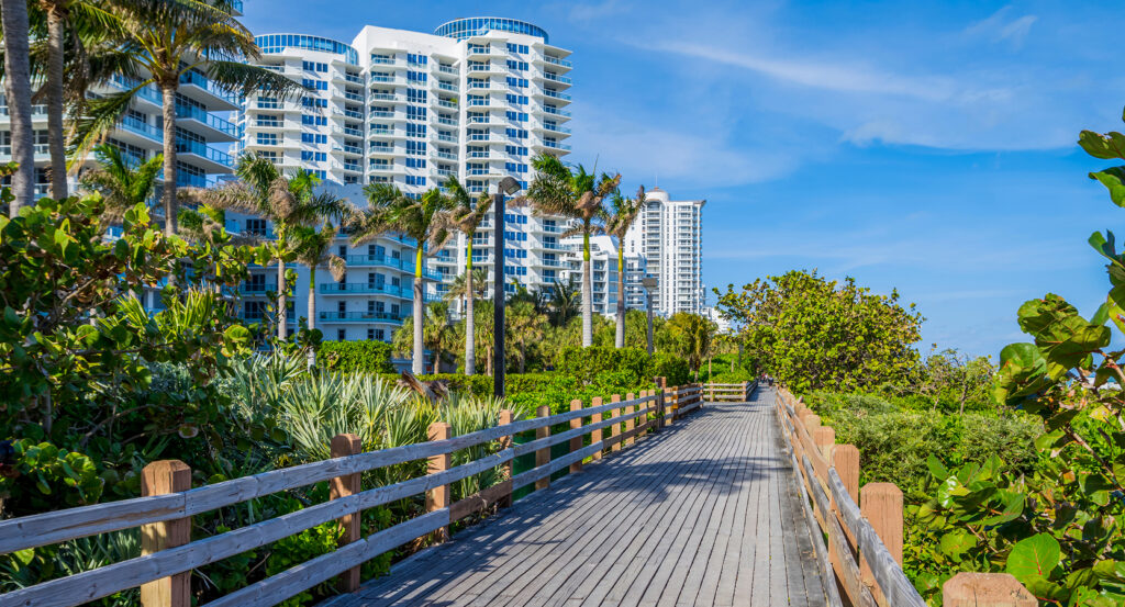 View of Miami Beach oceanfront from the boardwalk with tall condos and blue skies