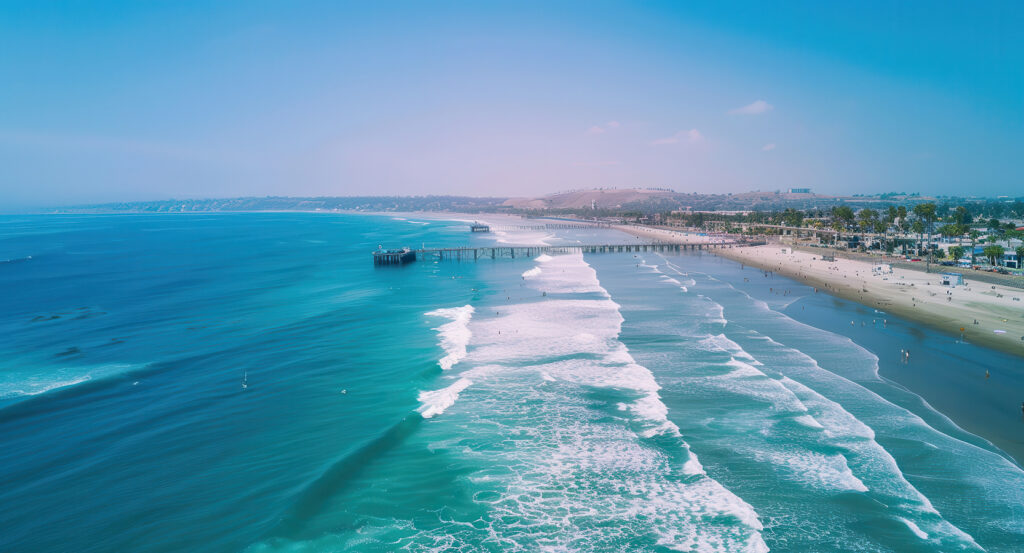 Surfers catching waves near the pier at Mission Beach on a bright, sunny day.