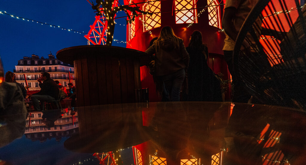 Guests gathering at Moulin Rouge with red lights and cabaret atmosphere