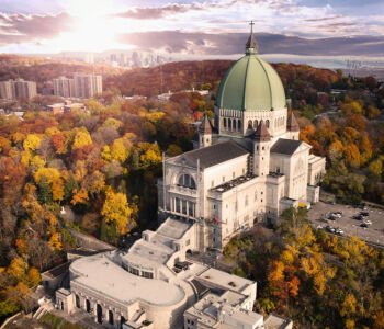Aerial view of Saint Joseph’s Oratory at golden hour surrounded by autumn trees and cityscape.