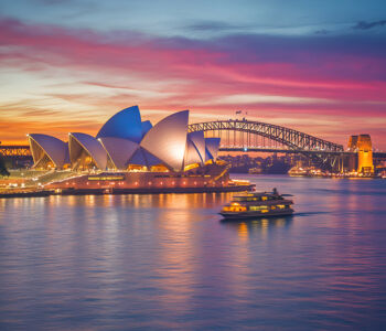Sydney Opera House glowing at sunset with ferry in the harbor
