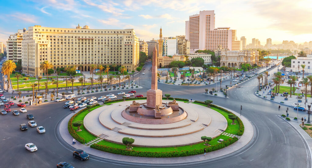 Tahrir Square at sunset with traffic and city skyline