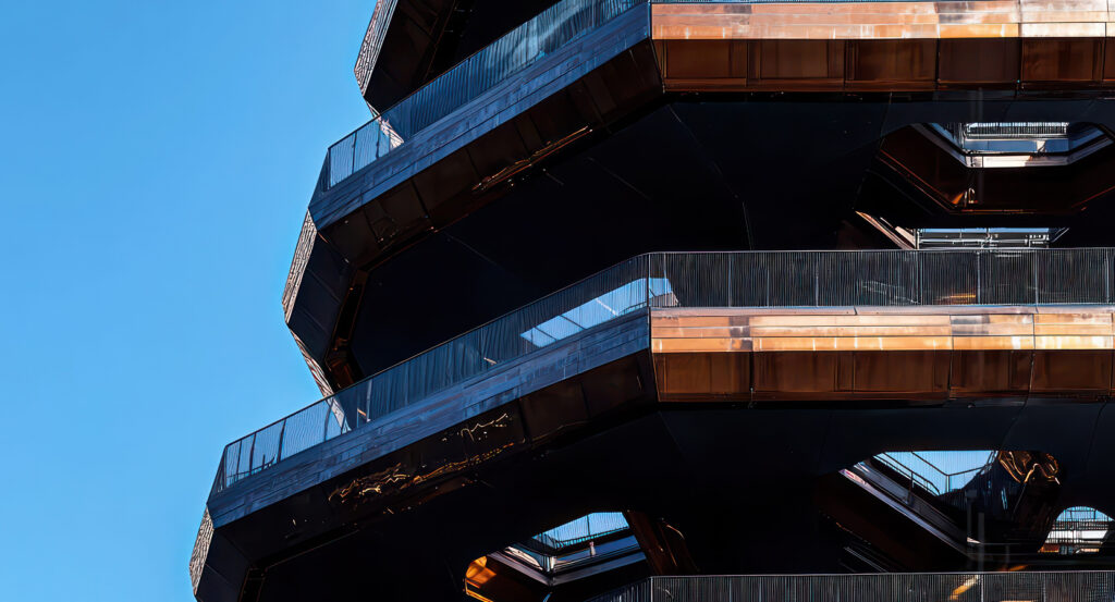 Modern architectural detail of The Vessel in NYC against a clear blue sky.
