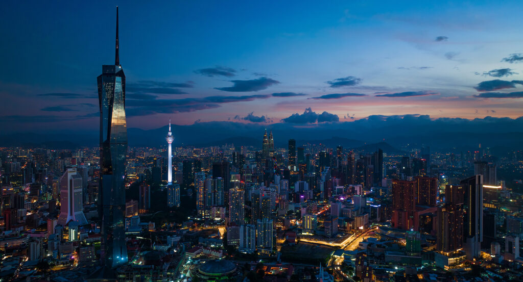 Skyline of Kuala Lumpur with Merdeka 118 tower illuminated against evening sky