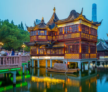 Yu Garden’s traditional pavilions glowing with warm lantern light above still water at night.