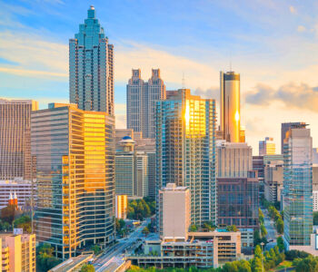 Atlanta skyline glowing at sunset with Midtown skyscrapers reflecting golden light across the city.