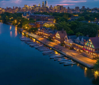 Boathouse Row illuminated at dusk with colorful lights reflecting across the Schuylkill River in Philadelphia.