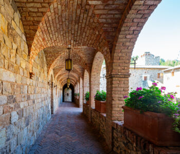 Stone archway corridor at Castello di Amorosa with warm light and vineyard views.