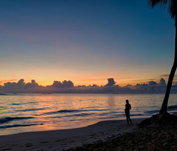 Silhouette of a person standing on a Punta Cana beach at sunrise.