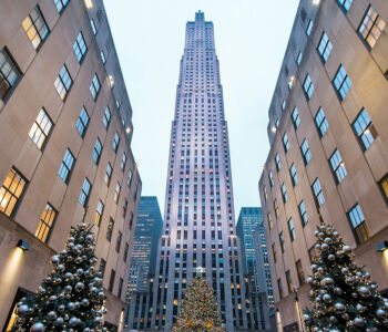 Rockefeller Center Christmas tree and skyscraper in New York City, framed by holiday lights and decorations.