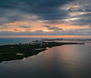Sunset over Nichupté Lagoon with calm water and hotel zone skyline in Cancun.