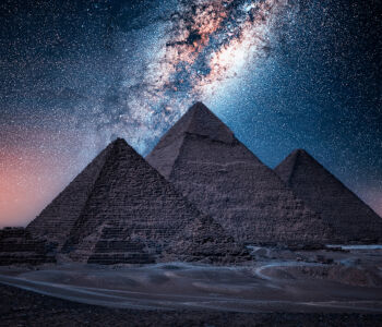 The Pyramids of Giza beneath a star-filled night sky and Milky Way.