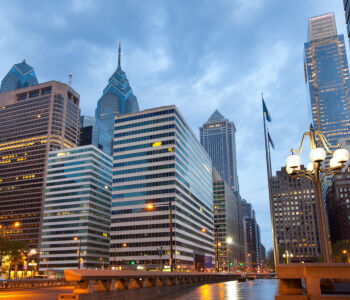 Center City Philadelphia skyline at blue hour, featuring modern high-rise buildings above the river.
