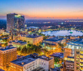 Aerial view of downtown Orlando and Lake Eola at sunset with city lights.