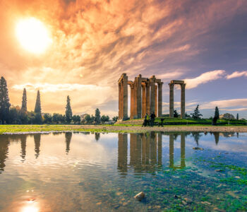 Temple of Olympian Zeus reflected in a still pool at sunset with dramatic clouds over Athens.